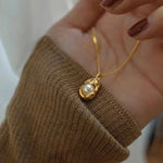 Caellia 14K gold dainty freshwater pearl pendant necklace held in a hand.