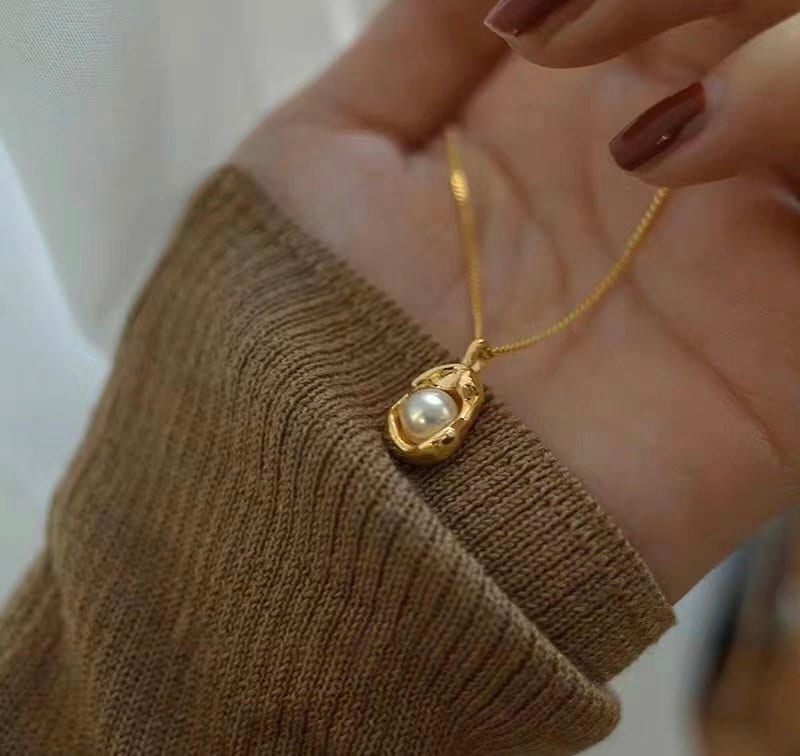 Caellia 14K gold dainty freshwater pearl pendant necklace held in a hand.