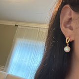 Casual close-up of a gold knot freshwater pearl drop earring worn