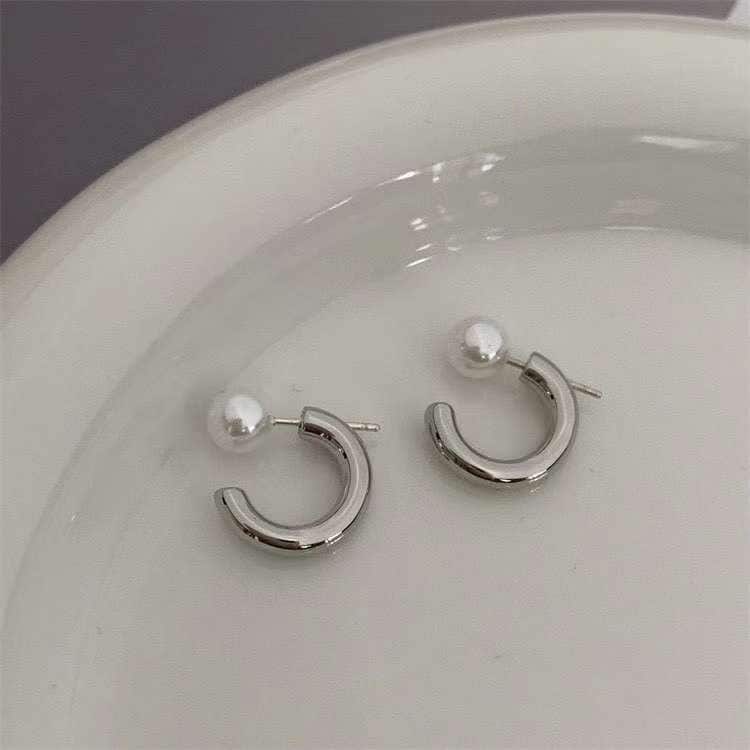 Caellia silver-toned hoop earrings featuring a single freshwater pearl on a white surface.