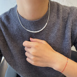 A CAELLIA minimalist freshwater pearl necklace worn with a grey sweater.