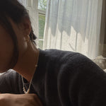 A person wearing Caellia 14K gold filled freshwater pearl hoop earrings.