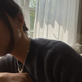 A person wearing Caellia 14K gold filled freshwater pearl hoop earrings.