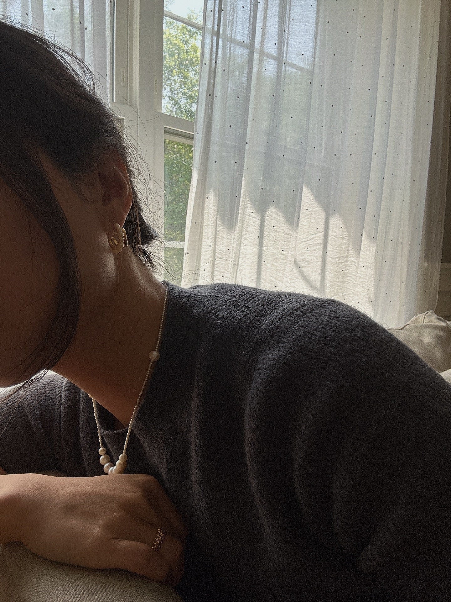 A person wearing Caellia 14K gold filled freshwater pearl hoop earrings.