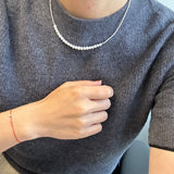 A person wears a CAELLIA minimalist freshwater pearl necklace with a grey sweater.