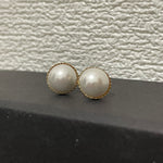 CAELLIA gold-plated stud earrings featuring lustrous round pearls with a delicate textured rim.