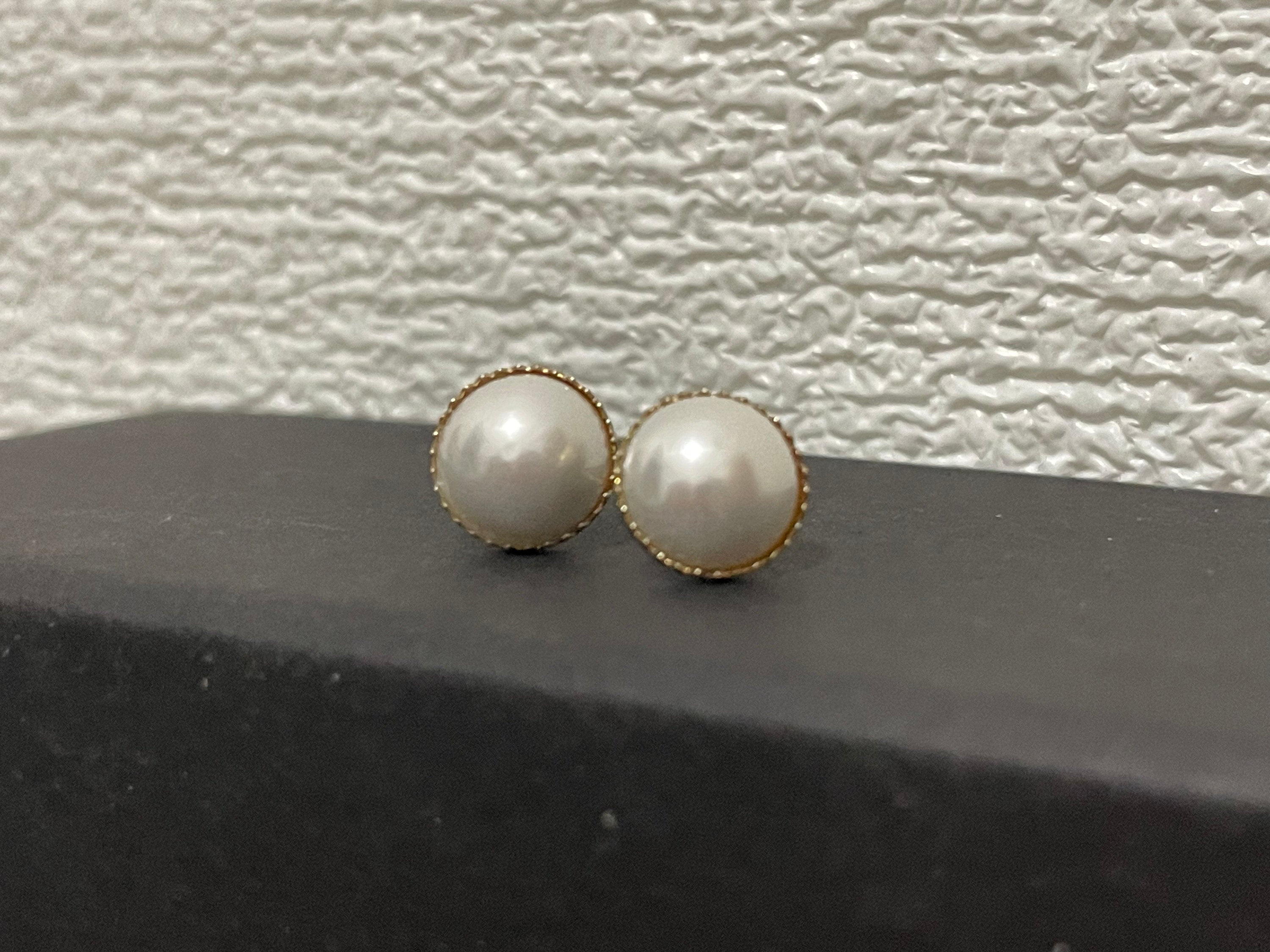 CAELLIA gold-plated stud earrings featuring lustrous round pearls with a delicate textured rim.