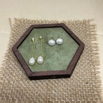 CAELLIA gold-plated pearl dangle earrings and stud earrings displayed on a green hexagonal tray.
