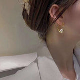 Freshwater pearl heart earrings on a woman's ear.