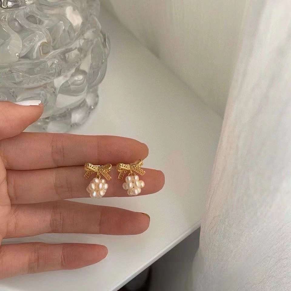 Caellia 14K gold bowknot earrings featuring clusters of small freshwater pearls.