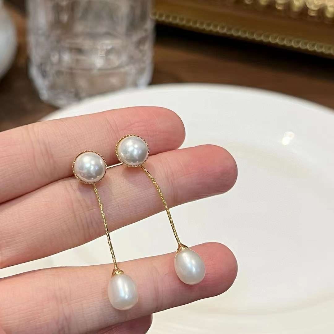CAELLIA gold-plated dangle earrings featuring a round pearl stud connected to a teardrop pearl.
