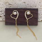 CAELLIA heart-shaped 18k gold plated dangle earrings featuring a pearl and delicate gold chains.