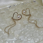 CAELLIA heart-shaped 18k gold plated dangle earrings featuring a central pearl and delicate chain.