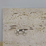 CAELLIA freshwater pearl rhomboid stud earrings featuring a four-pearl design on a stone background.