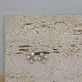 CAELLIA freshwater pearl rhomboid stud earrings featuring a four-pearl design on a stone background.