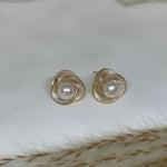 CAELLIA stud earrings featuring a central freshwater pearl surrounded by a gold-rimmed flower design.