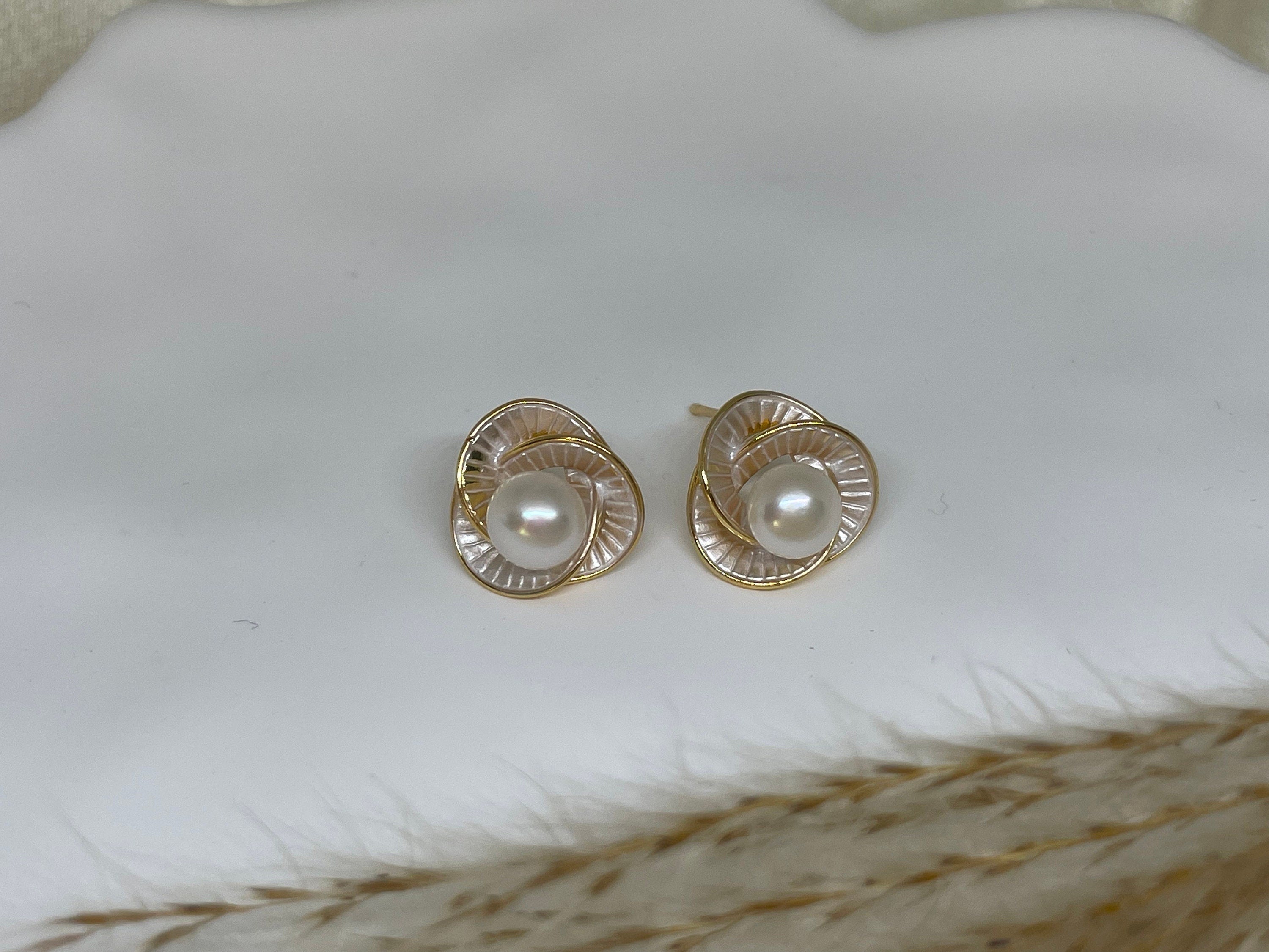 CAELLIA stud earrings featuring a central freshwater pearl surrounded by a gold-rimmed flower design.