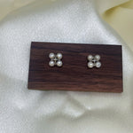 CAELLIA freshwater pearl rhomboid stud earrings displayed on a wooden stand.