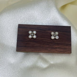 CAELLIA freshwater pearl rhomboid stud earrings displayed on a wooden stand.