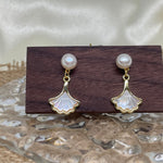 Caellia 14K gold earrings featuring a freshwater pearl stud and a mother-of-pearl fan dangle.