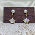 Caellia 14K gold earrings featuring a freshwater pearl stud and a mother-of-pearl fan dangle.
