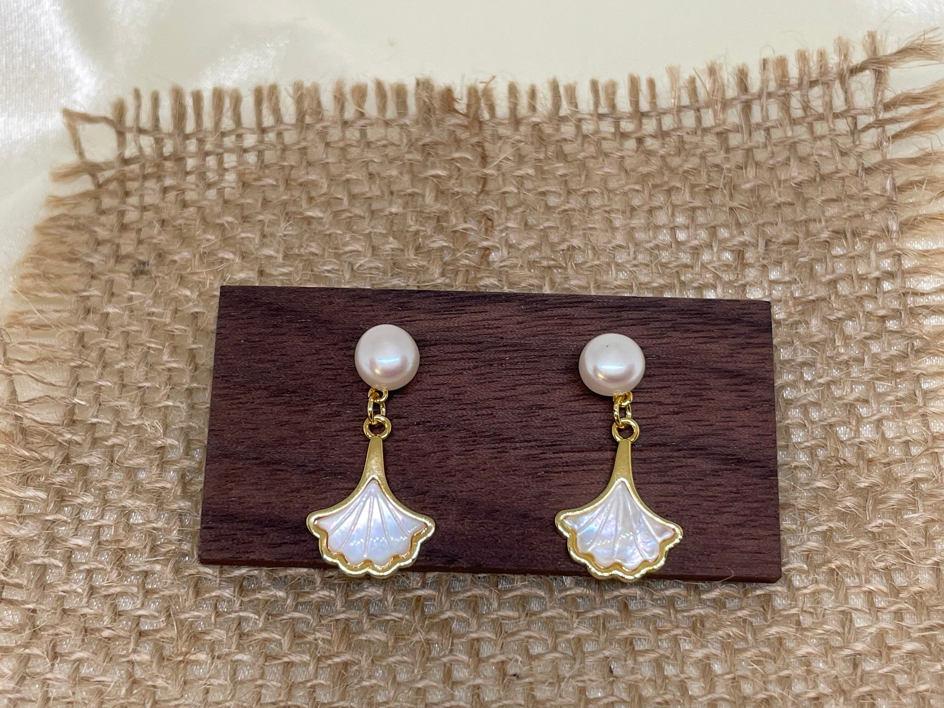Caellia 14K gold earrings featuring a freshwater pearl stud and a mother-of-pearl fan drop.
