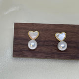 Caellia 14K gold stud earrings featuring a heart-shaped fritillaria shell above a freshwater pearl.