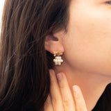 A model wears Caellia 14K gold bowknot earrings featuring a cluster of freshwater pearls.