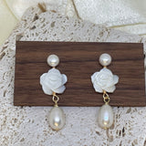 Caellia 14K gold dangle earrings featuring a white camellia flower stud and a freshwater pearl.
