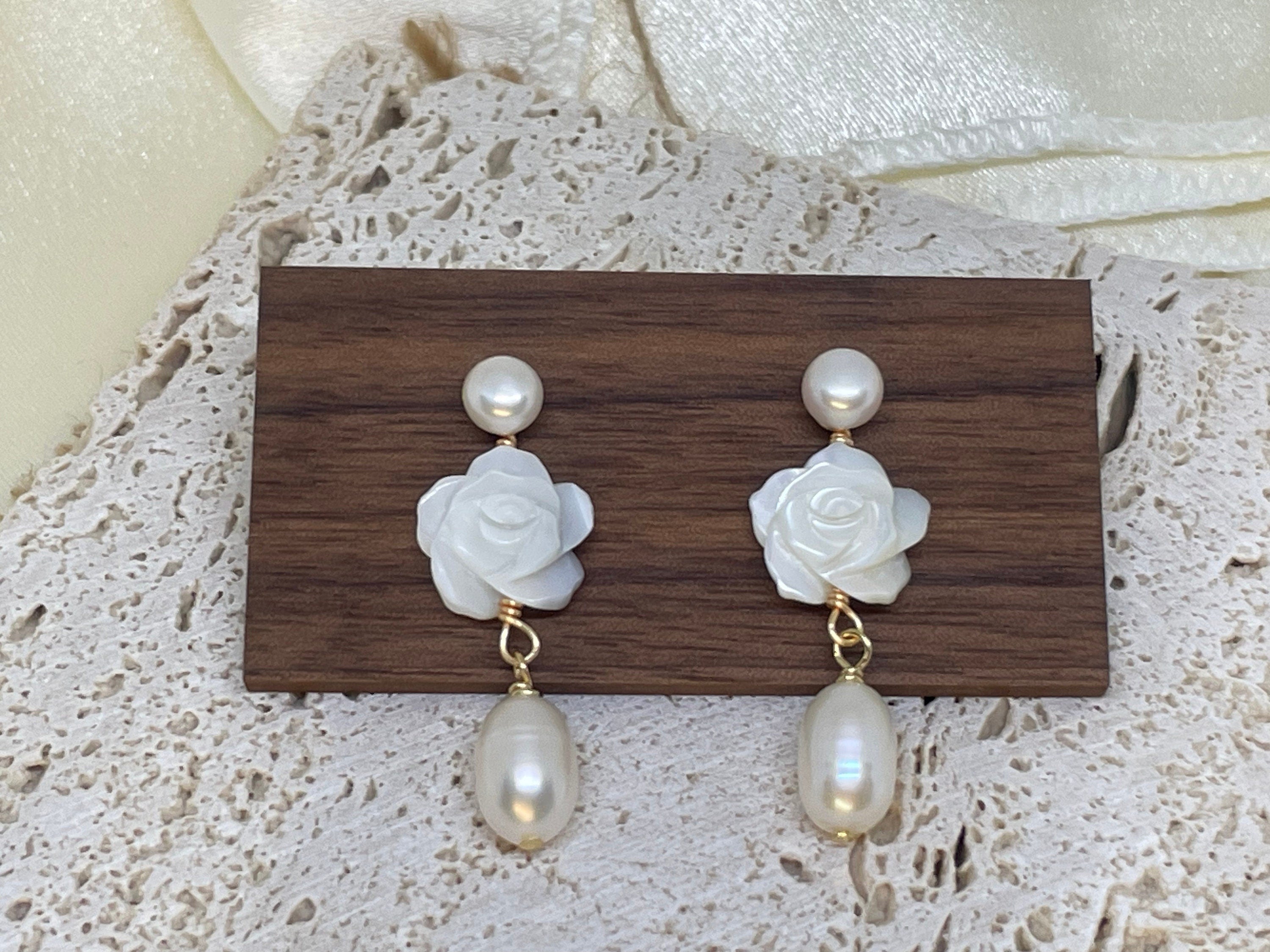 Caellia 14K gold dangle earrings featuring a white camellia flower stud and a freshwater pearl.