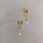 Caellia 14K gold bow earrings featuring dangling freshwater pearls.