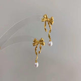 Caellia 14K gold bow earrings featuring dangling freshwater pearls.