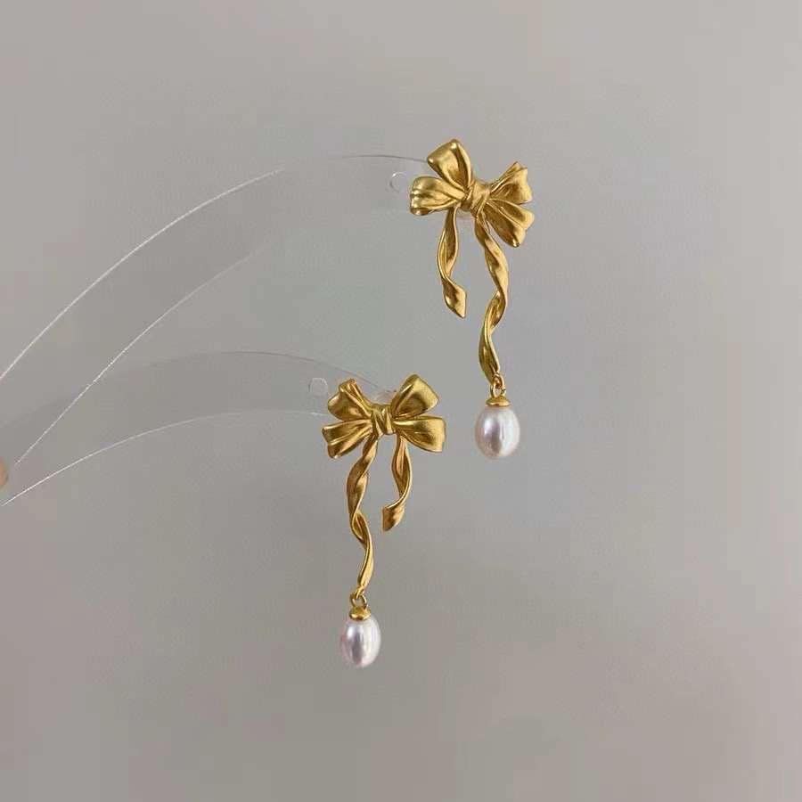 Caellia 14K gold bow earrings featuring dangling freshwater pearls.
