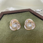 CAELLIA stud earrings featuring a central freshwater pearl surrounded by a gold-rimmed petal design.