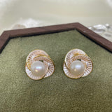 CAELLIA stud earrings featuring a central freshwater pearl surrounded by a gold-rimmed petal design.