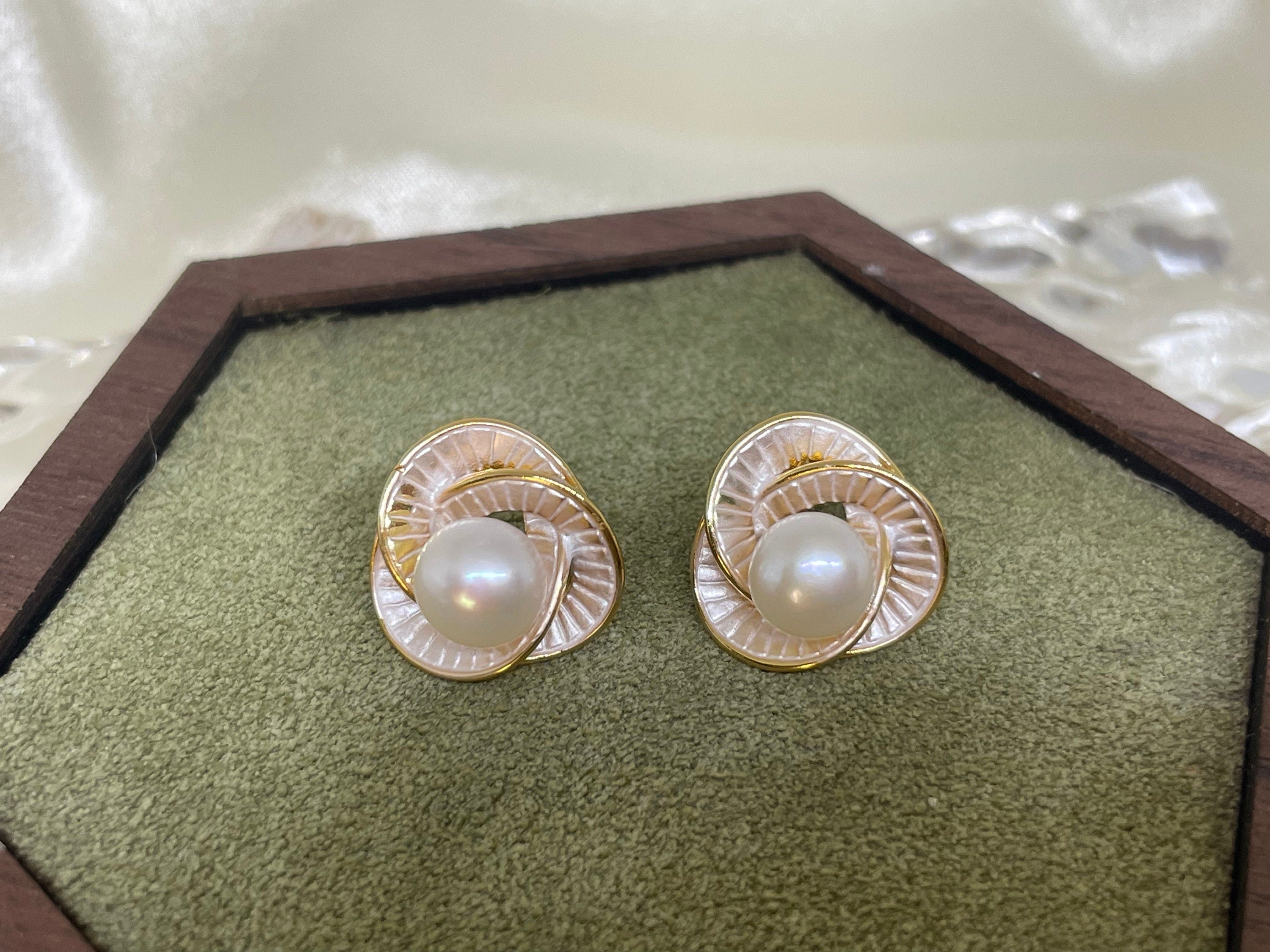 CAELLIA stud earrings featuring a central freshwater pearl surrounded by a gold-rimmed petal design.