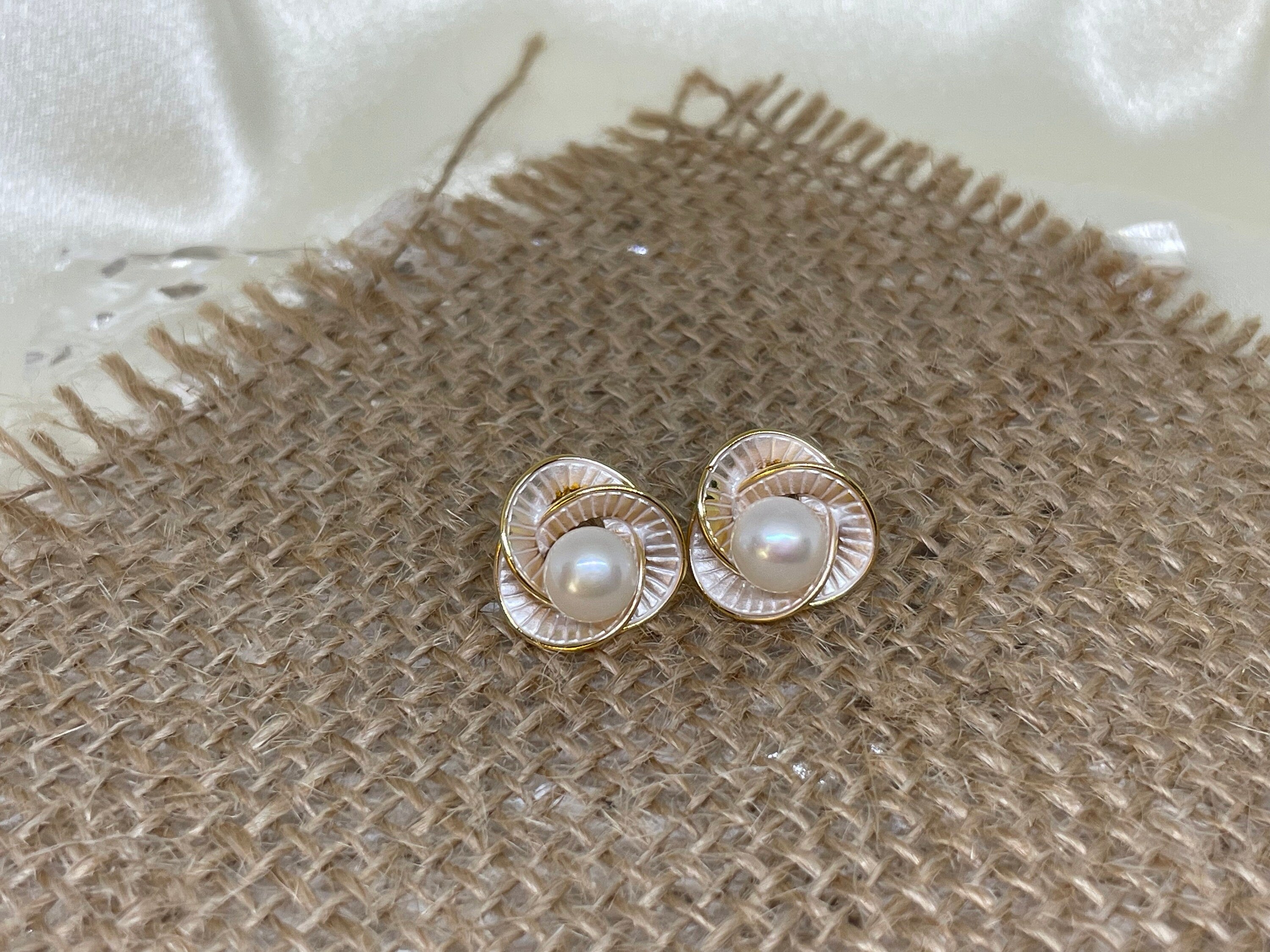 A pair of gold-tone CAELLIA flower stud earrings featuring a central freshwater pearl.