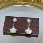 Caellia 14K gold earrings featuring a freshwater pearl stud and a mother-of-pearl fan dangle.