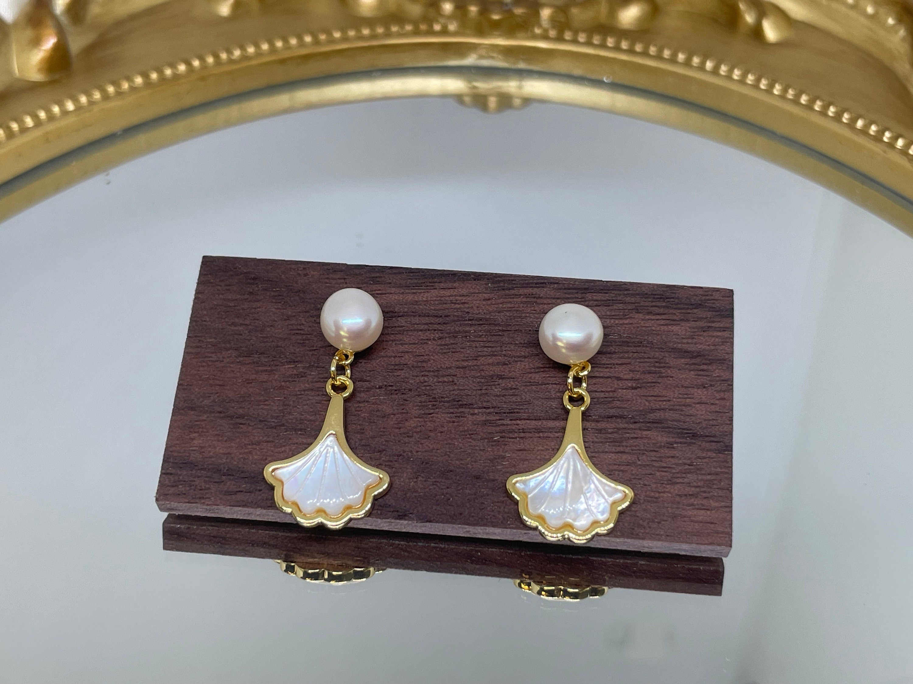 Caellia 14K gold earrings featuring a freshwater pearl stud and a mother-of-pearl fan dangle.