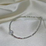 A CAELLIA freshwater pearl and 925 sterling silver beaded bracelet on a white satin background.