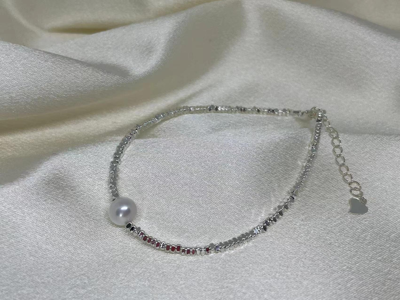 A CAELLIA freshwater pearl and 925 sterling silver beaded bracelet on a white satin background.