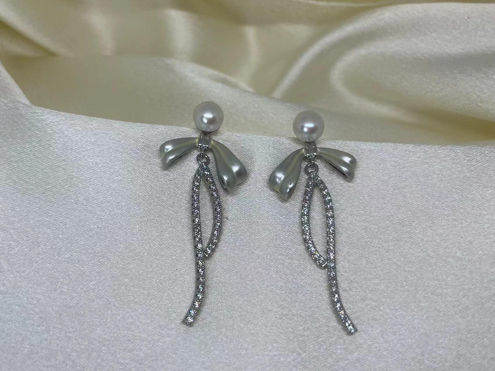 CAELLIA sterling silver dangle earrings featuring a pearl-topped bow and a crystal-lined drop.