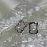 CAELLIA silver stud earrings featuring a freshwater pearl inside a textured square frame.