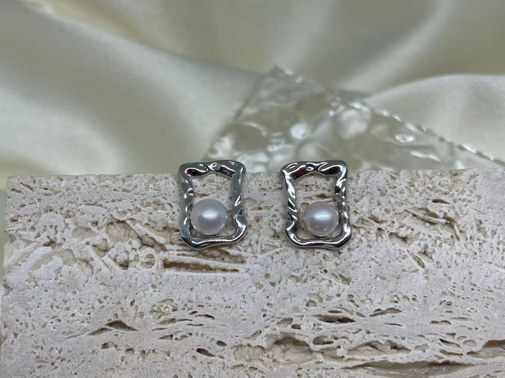 CAELLIA silver stud earrings featuring a lustrous freshwater pearl inside a modern square frame.