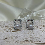CAELLIA silver stud earrings featuring a lustrous freshwater pearl inside a modern square frame.