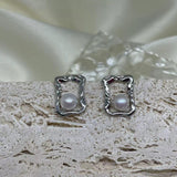 CAELLIA silver stud earrings featuring a lustrous freshwater pearl inside a modern square frame.