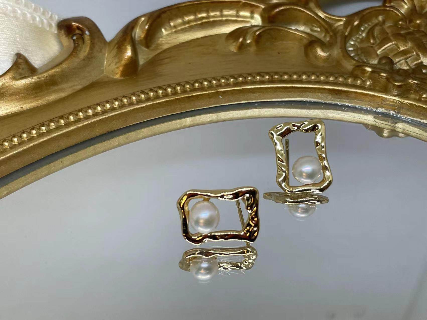 CAELLIA gold plated stud earrings featuring a lustrous freshwater pearl in a textured square frame.
