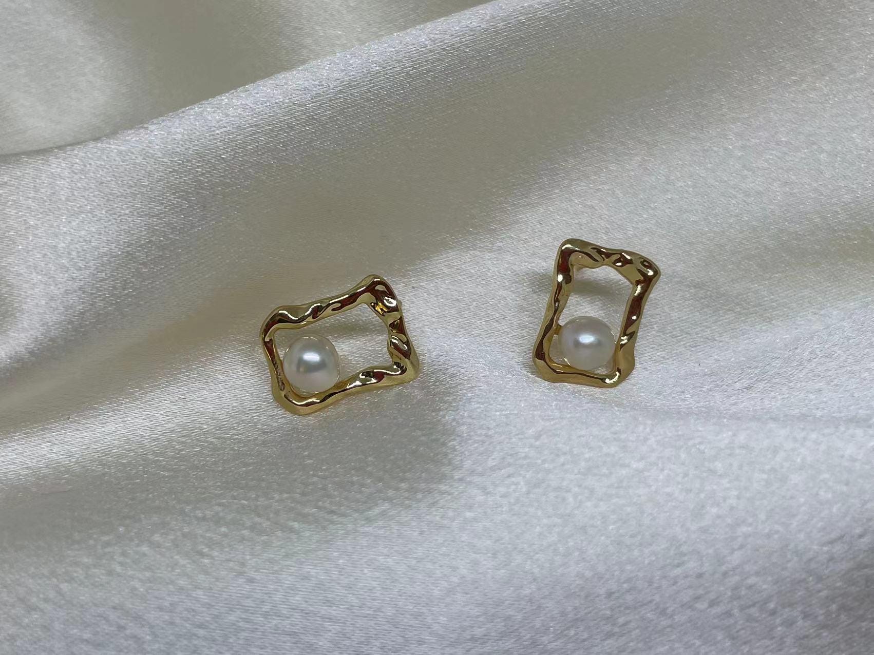 CAELLIA gold plated stud earrings featuring a freshwater pearl inside a textured quadrate frame.