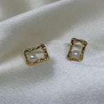 CAELLIA gold plated stud earrings featuring a freshwater pearl inside a textured quadrate frame.