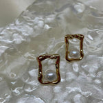 CAELLIA gold plated stud earrings featuring a lustrous freshwater pearl in a textured square frame.
